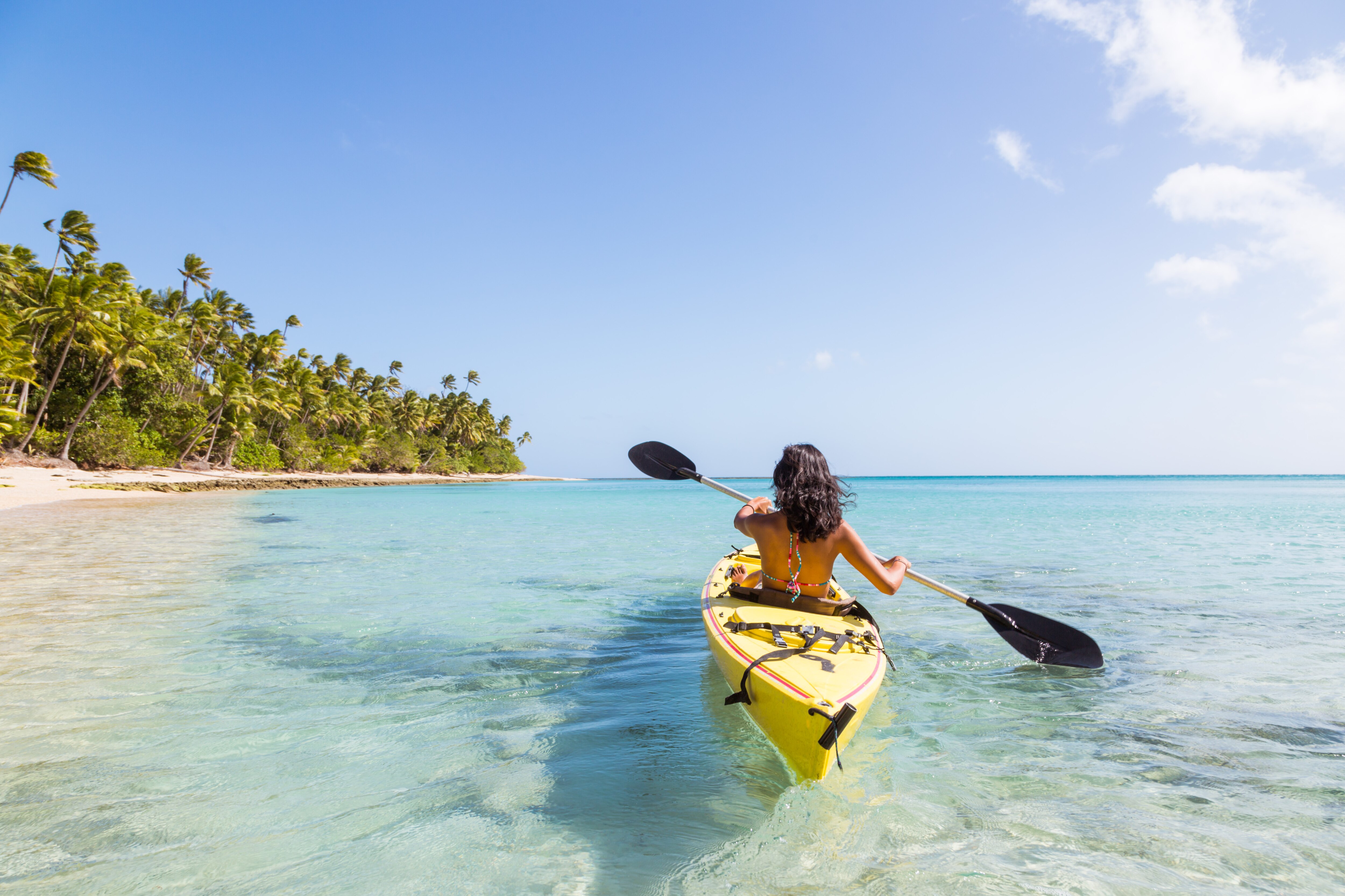 Woman kayaking by a tropical island in crystal clear water